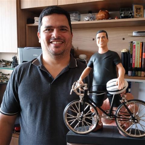 Cliente segurando sua miniatura 3D de ciclista ao lado de uma bicicleta em miniatura